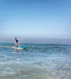 Woman surfing over sea against sky