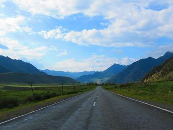 Empty road leading towards mountains against sky