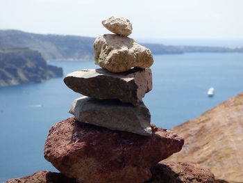 Stack of rocks by sea against sky