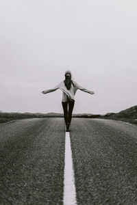 Woman with arms raised while standing on land against sky