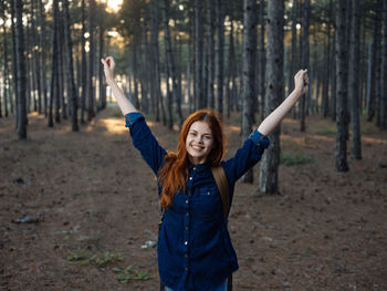 Happy young woman standing in forest