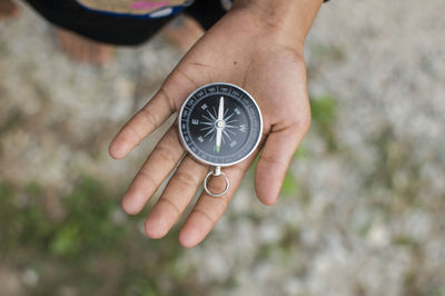 Close-up of woman holding navigational compass on field