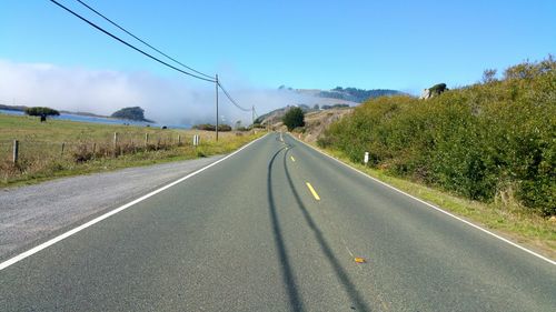 Road passing through foggy landscape against sky