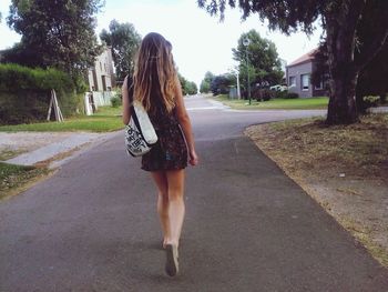 Rear view of woman walking on road