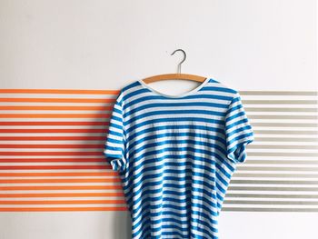 Striped t-shirt hanging on coathanger against patterned wall