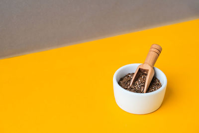 Wooden spoon with flax seeds lies in a white mortar on a yellow background. healthy eating. 