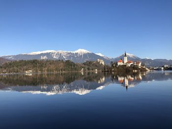 Scenic view of lake and mountains against clear blue sky