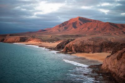 Scenic view of mountains and sea against cloudy sky