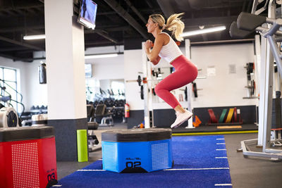 A woman box jumping in the gym.