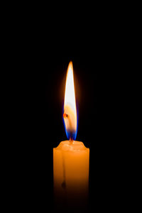 Close-up of lit candle in darkroom