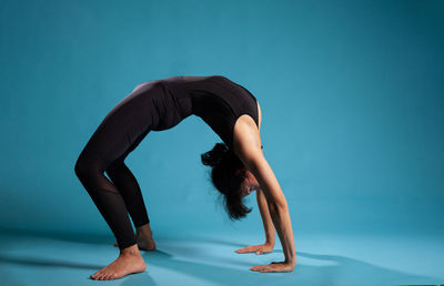Low section of woman exercising against blue background