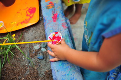 Midsection of child holding small container with paint