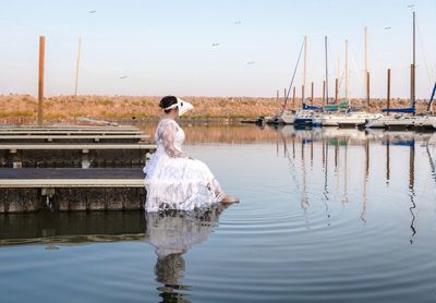 Woman standing by lake against sky