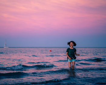 Woman standing on beach against sky during sunset