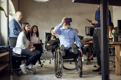 Businessman with disability wearing vr simulator amidst colleagues at creative office