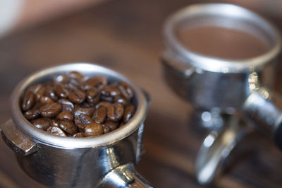 Close-up of ground coffee and roasted coffee beans in filters on table