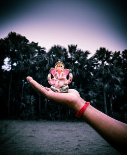 Midsection of woman holding pink plant against trees