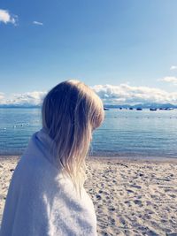 Side view of girl wrapped in towel at beach by lake tahoe against sky