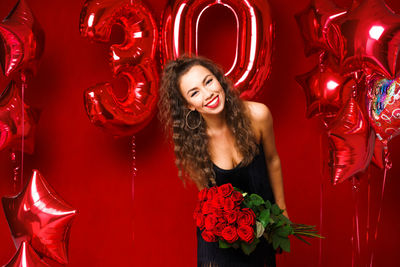 Beautiful young woman on a red background with red balloons