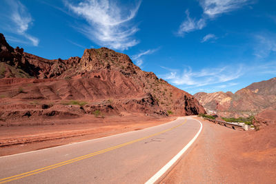 Road leading towards mountains against sky