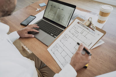 Architect with blueprint working at desk