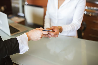 Mature woman taking document from female receptionist at hotel desk