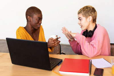 Cheerful lesbian couple talking while working at home