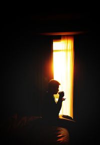 Side view of woman sitting on bed at home