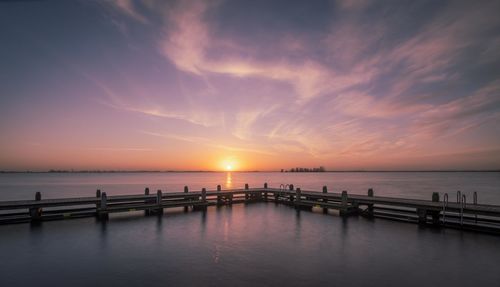 Pier over sea against sky during sunset
