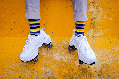 Low section of girl with roller skates against yellow wall