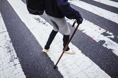Single person walking across the street while using a cane walking stick in new york city