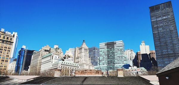 Modern buildings in city against clear blue sky