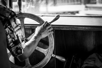 Midsection of man holding steering wheel in boat