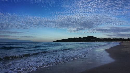 Scenic view of beach against sky at sunset