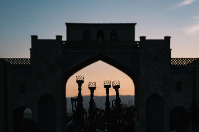 Silhouette people in front of building against sky during sunset