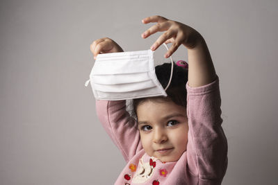 Portrait of cute girl with arms raised against gray background