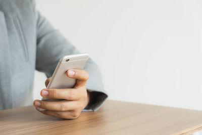 Midsection of man using mobile phone on table