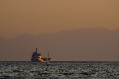 Silhouette ship sailing on sea against clear sky during sunset