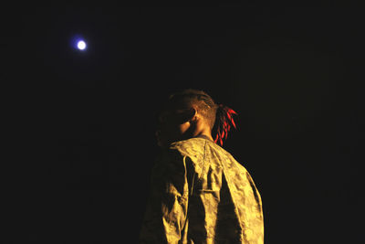 Low angle view of woman standing against black background