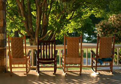 Empty wooden chairs against trees at porch