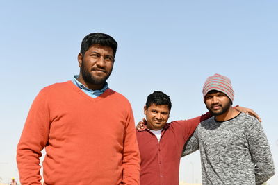 Three friends standing outdoors against sky