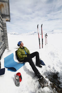 Woman resting in front of mountain cabin