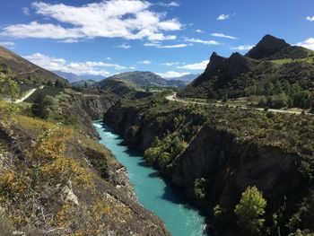 Scenic view of river by mountains against sky