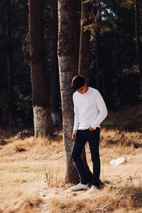 Full length of young man standing on field in forest