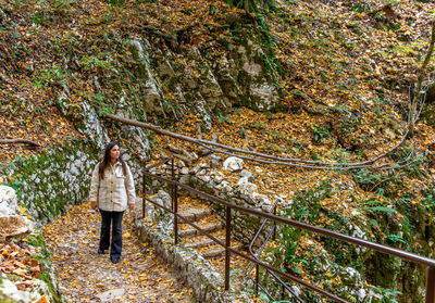 Young woman walking on foot path in plitvice lakes national park in croatia in autumn