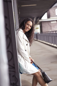 Portrait of smiling beautiful woman standing below bridge