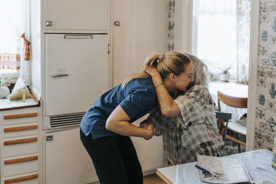 Senior woman embracing female care assistant at home