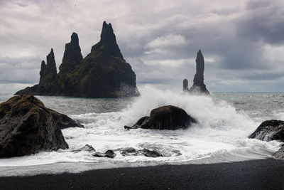 Scenic view of rocks in sea against cloudy sky