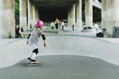 Rear view of girl skateboarding at park