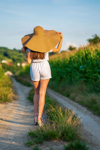 Young beautiful woman with summer hat in the corn field.